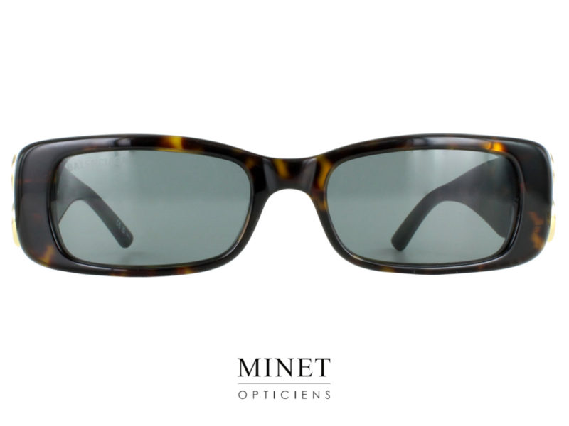 Les lunettes solaires Balenciaga BB096S sont l'incarnation parfaite de l'élégance et du style audacieux de la marque. Conçues spécialement pour les femmes, ces lunettes arborent une forme fine et rectangulaire qui ajoute une touche de sophistication à toute tenue. La face de ces lunettes est fabriquée en acétate de haute qualité, offrant à la fois durabilité et esthétique raffinée. Les tempes, quant à elles, sont légèrement plus épaisses, créant un contraste subtil qui met en valeur le design global. Les branches de ces lunettes sont remarquablement larges, atteignant la même largeur que la face. Cela crée un effet visuel saisissant, accentuant le caractère distinctif de ce modèle. L'un des éléments emblématiques des Balenciaga BB096S est le logo de la marque, deux grands B dorés, qui est intégré de manière élégante dans les branches. Ce logo emblématique ajoute une touche de glamour et de reconnaissance à ces lunettes de soleil.